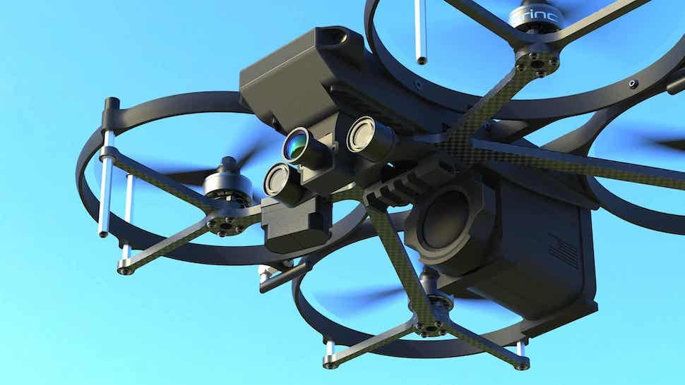 A quadcopter drone in flight against a blue sky